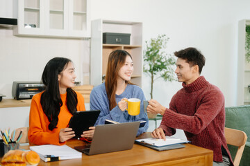 Obraz premium Teamwork and creativity with young adults collaborating on laptops and tablets in a cozy workspace.