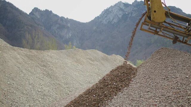 Close-up view when a machinery in quarry sorts rock and pouring gravel.