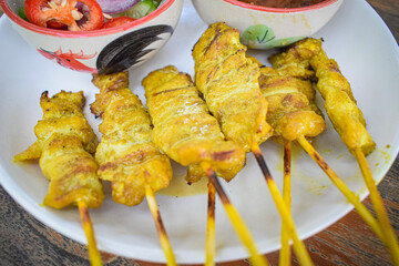 The photograph showcases a plate of beautifully arranged skewered pork satay.  
