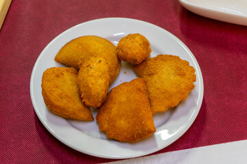 Traditional Portuguese appetizers: crispy rissóis and codfish cakes served on a rustic table in a restaurant setting. A delicious glimpse of Portuguese cuisine.