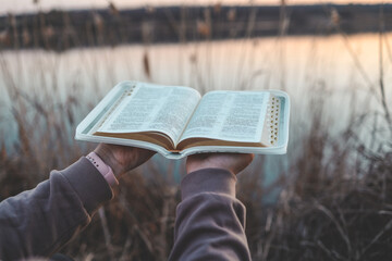 Bible in the hands of a girl, concept morning prayer in nature