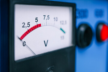 Close-up of a voltage meter displaying readings on a white dial with a red and green scale....
