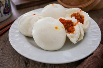 steamed stuff bun,steamed dumpling,stuffed steamed bun,thai called sarapao in white plate on wooden background