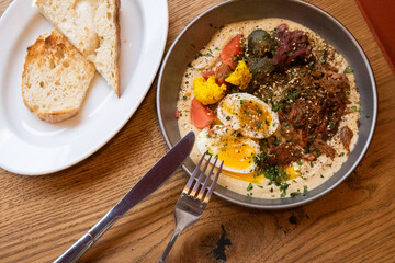 large plate of hummus, pork and egg with vegetables