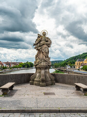 Obraz premium Ornate Stone Statue on a Historic Bridge with Scenic Backdrop, Wurzburg, Germany