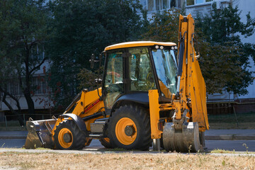 A bulldozer with a large bucket stands on an asphalt road