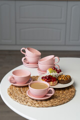 Pink ceramic cup and saucer on light dining table in dining room