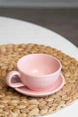 Pink ceramic cup and saucer on light dining table in dining room