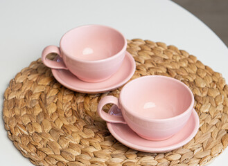 Pink ceramic cup and saucer on light dining table in dining room