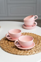 Pink ceramic cup and saucer on light dining table in dining room