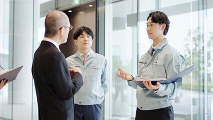 ロビーで話をするビジネスマンと作業服を着た男性