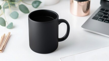A black coffee mug sits on a white desk next to a laptop