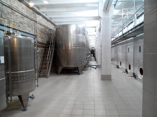 Modern winery interior with metal fermentation tanks and tiled flooring