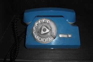 Vintage blue rotary phone displayed on wooden surface in a nostalgic setting