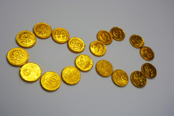 Beautiful, large gold coins, cents with a dollar $ sign are located on a white plastic background. Money candies, a chocolate bar in a gold metal shell.