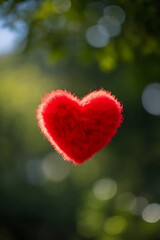 A soft, fuzzy red heart floats gently in a natural setting.
