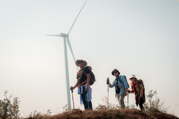 Hiker or explorer on journey carrying backpack, trekking poles hiking landscape with wind turbines farm background trekking and trail exploration holiday ecotourism concept.