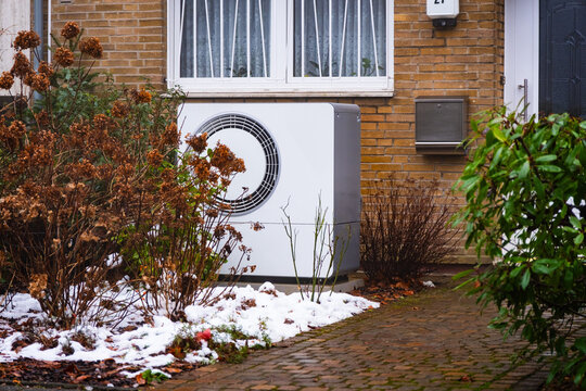 Eine W&auml;rmepumpe hinter verbl&uuml;hten Hortensienb&uuml;schen in einem Vorgarten in D&uuml;sseldorf