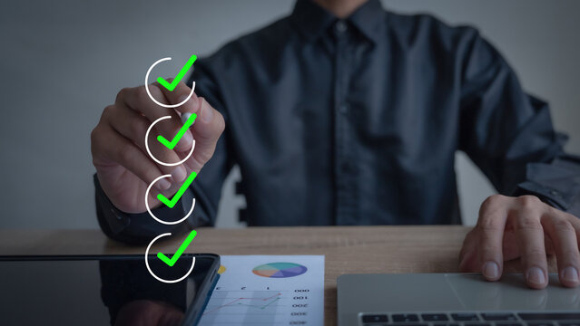 Business Performance Checklist Businessman uses hand to make a mark to indicate completion of online survey or checklist evaluation.
