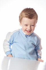 Emotional baby in shirt and blue jumper on white background