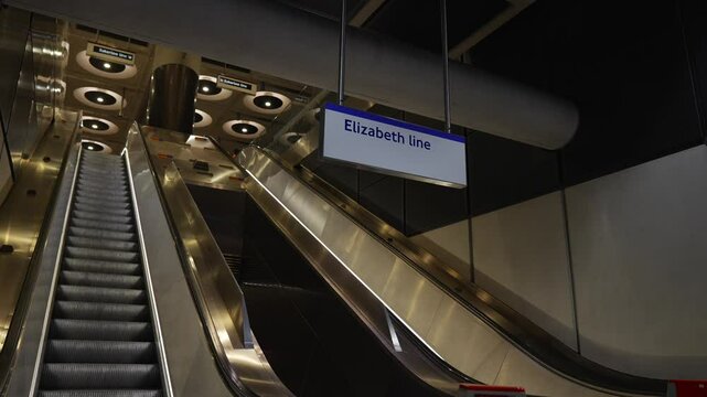 The escalator is silver and has a sign that says Elizabeth Line. The escalator is empty