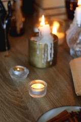 Books, lit candles, red wine, snacks and various deocration on the table. Dark academia or Halloween concept. Selective focus.