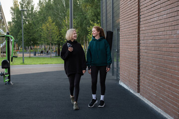 Two happy sporty women cuddle after an outdoor fitness workout in a summer park. The concept of doing sports with friends