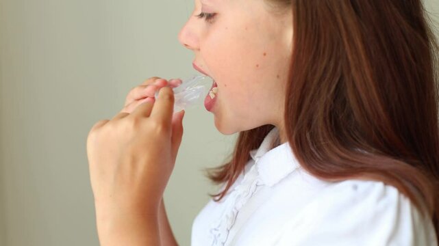 A young girl demonstrates how to put on and showcase her orthodontic retainer designed to correct her bite and improve her smile. This close-up footage provides insights into the importance of dental 