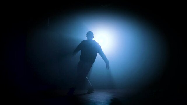 Silhouette of a man dancing break dance in a dark studio Dancer artist performing. High quality 4k footage