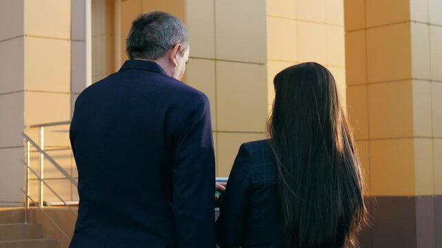 Workers walk along street engrossed in discussion about business. Workers consider innovative approaches as part of business strategies. Workers discuss adapting business to changing conditions