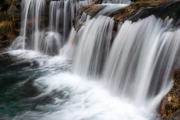 Mesmerizing waterfall cascading over rocky terrain, with silky smooth water flows creating a serene and tranquil nature scene, perfect for landscape lovers.