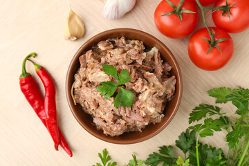 Canned meat in bowl, parsley, tomatoes, garlic and chili peppers on wooden table, top view