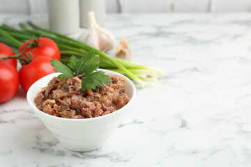 Canned meat in bowl, parsley, tomatoes and green onions on white marble table, closeup. Space for text