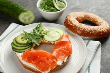 Delicious bagel with salmon, cream cheese, cucumber and avocado on grey table, closeup
