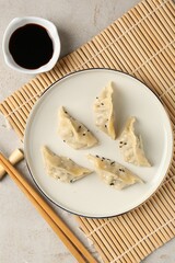 Delicious gyoza dumplings with sesame seeds served on light table, top view