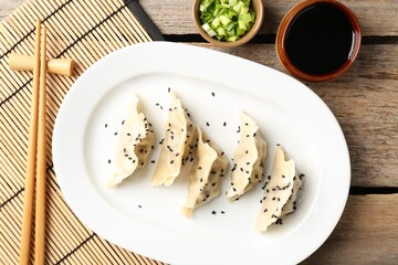 Delicious gyoza dumplings with sesame seeds served on wooden table, top view