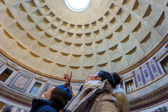 Mother and daughter tourists gazing upward, admiring architectural marvel of Pantheon's oculus in historic Rome, Italy
