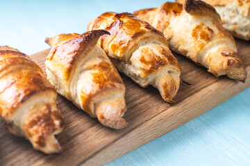 Croissants on a wooden board on a blue background.