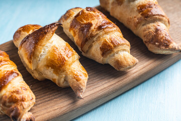 Croissants on a wooden board on a blue background.