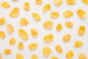 Yellow dry corn flakes on light gray table background. Closeup. Food pattern. Top down view.