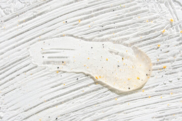 Close up of creamy white sauce with specks and smudges on a flat surface.