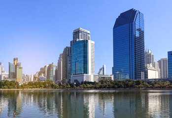 Fototapeta premium Beautiful Benchakitti Park, skyscrapers against the backdrop of a reservoir and palm trees, open public space, Bangkok, Thailand