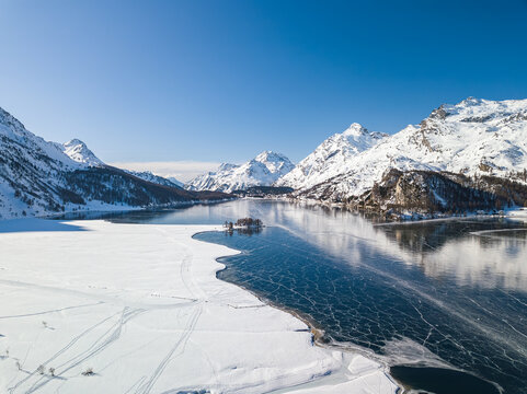 Aerial view of the frozen lake of Silsersee with people walking on the lake surface - Maloja and Plaun da Lej in St. Moritz, Switzerland
