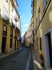 Charming cobblestone street in Lisbon, Portugal, with traditional buildings and clothes hanging.