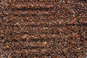 Coarse ground coffee texture with dark brown granules and shimmering highlights.