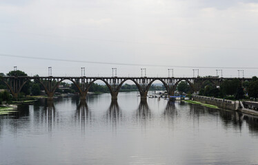 Stunning arched bridge over calm river, reflecting cityscape.