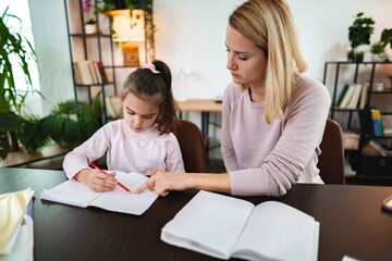 Obraz premium Engaging in a thoughtful learning moment between mother and daughter at home