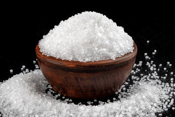 A clay cup with salt and salt sprinkled around it. table salt.