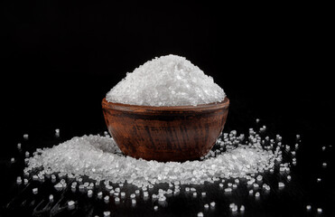 A clay cup with salt and salt sprinkled around it. table salt.
