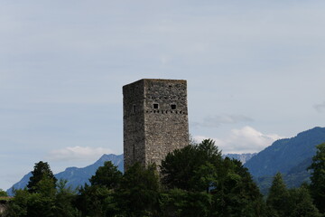 Burg Turmruine ragt aus dem Wald hervor, Alpen Berge im Hintergrund